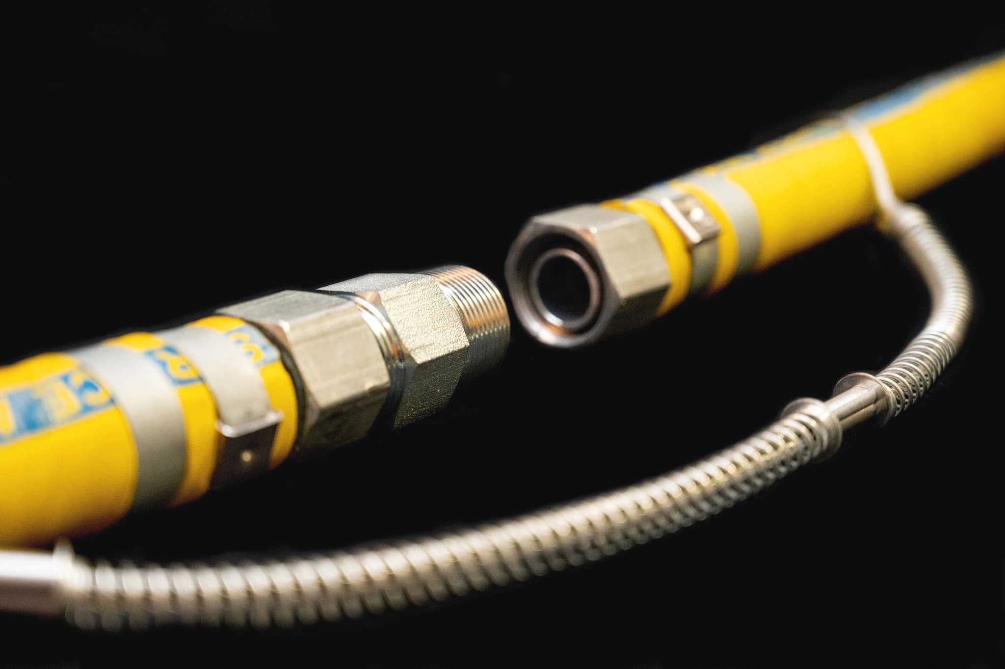 Hexa 1 inch MNPT Hex Nipple installed on a yellow industrial hose against a black background